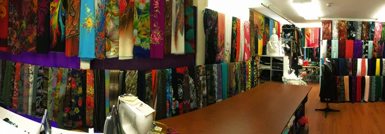 A view inside the shop, with a cutting table, sewing machines, and fabric displays